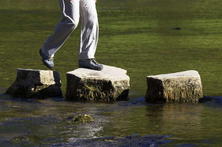 crossing three stepping stones in a riverの写真素材