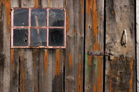 Old weathered and worn wooden planks with door and pink framed windowの写真素材