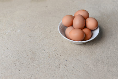 eggs in white bowl on cement floor with copy space