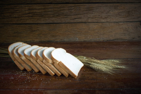 Sliced bread and wheat on wooden tableの写真素材