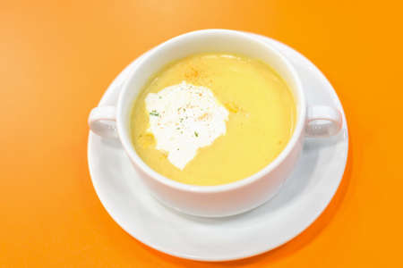 Corn Soup in white bowl on orange backgroundの写真素材