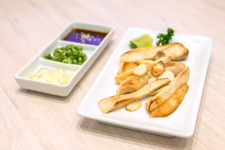 Stir fried eringii mushroom and garlic on white plate, japanese food.の写真素材