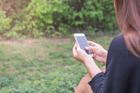 Asian woman with smartphone outdoors in park. Closeup of female hands and smart phone.の写真素材