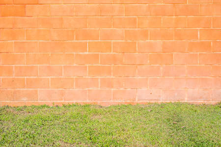 Orange brick wall background with green grass on floorの写真素材