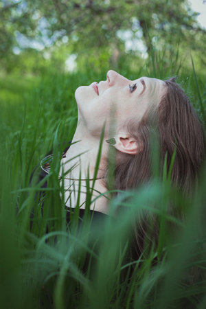 Close up woman in tall grass looking up at sky portrait picture. Enjoy garden picnic. Closeup side...