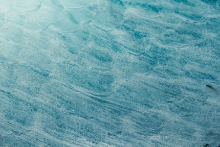 Close up blue wavy ice surface concept photo. Winter season. Top view photography with frozen water...