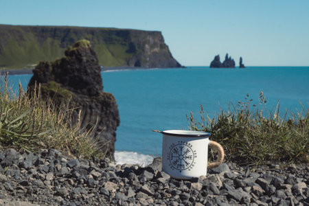 Close up metal cup on rock against azure lagoon concept photo. Front view photography with cliff and...