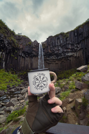 Close up man with mug against waterfall concept photo. Filling cup with water. First view hand...