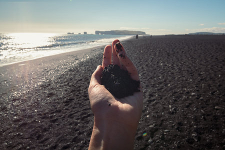 Close up female hand with sand concept photo. Seaside beauty. First person view photography with...