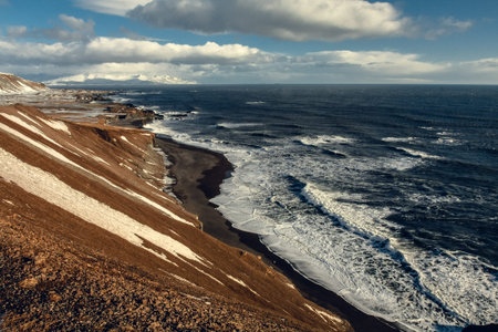 Volcanic beach with sea waves landscape photo. Beautiful nature scenery photography with cloudy sky...