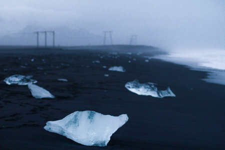 Close up small ice pieces on black sand concept photo. Reynisfjara beach. Front view photography...
