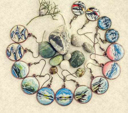 Close up craft earrings with landscapes and cityscapes concept photo. Top view photography with light table on background. High quality picture for wallpaper, travel blog, magazine, articleの写真素材