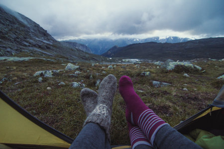 Close up hikers resting in tent at highland camp concept photo. First view person photography with overcast sky on background. High quality picture for wallpaper, travel blog, magazine, articleの写真素材
