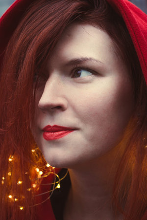 Close up happy woman with red lipstick and fairy lights portrait picture. Closeup side view...