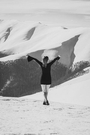 Slim lady in dress on ridge monochrome scenic photography. Picture of person with large mountains on background. High quality wallpaper. Photo concept for ads, travel blog, magazine, articleの写真素材