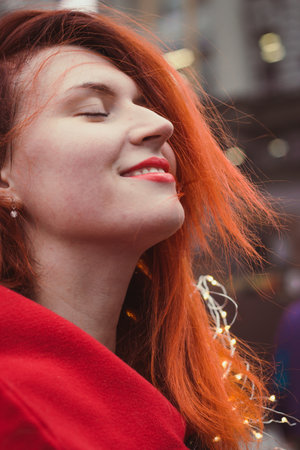 Close up smiling woman with fairy lights on street portrait picture. Closeup side view photography with blurry background. High quality photo for ads, travel blog, magazine, articleの写真素材