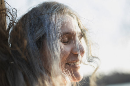 Close up tousled gray haired woman laughing with closed eyes portrait picture. Closeup side view photography with blurred background. High quality photo for ads, travel blog, magazine, articleの写真素材