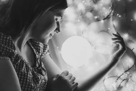 Close up sleeping lady with glowing lamp monochrome portrait picture. Closeup side view photography with fairy lights on background. High quality photo for ads, travel blog, magazine, articleの写真素材