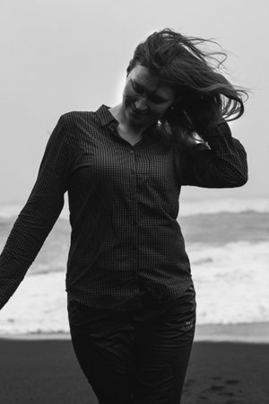 Close up funny woman on Iceland beach monochrome portrait picture. Closeup front view photography with stormy ocean on background. High quality photo for ads, travel blog, magazine, articleの写真素材