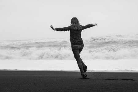 Happy tourist on black northern beach monochrome scenic photography. Picture of person with stormy...