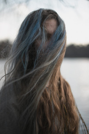 Close up long gray brown hair hiding woman face with wind portrait picture. Closeup front view...