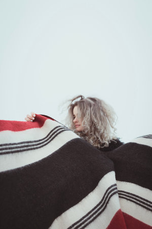 Elegant lady with floating woolen plaid outdoors portrait picture. Side view photography with grey cloudy sky on background. High quality photo for ads, travel blog, magazine, articleの写真素材