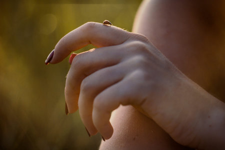 Close up woman holding ladybug on finger concept photo. Playing with insect outdoor. Front view photography with blurred background. High quality picture for wallpaper, travel blog, magazine, articleの写真素材
