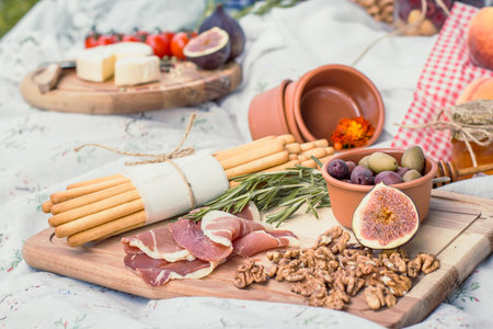 Close up delicious picnic food on blanket concept photo. Romantic summer outing. Front view photography with blurred background. High quality picture for wallpaper, travel blog, magazine, articleの写真素材