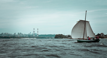Sailboat and waterfront industrial town landscape photo. Beautiful nature scenery photography with...