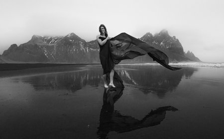 Stylish woman with waving cave on beach monochrome scenic photography. Picture of person with hills on background. High quality wallpaper. Photo concept for ads, travel blog, magazine, articleの写真素材