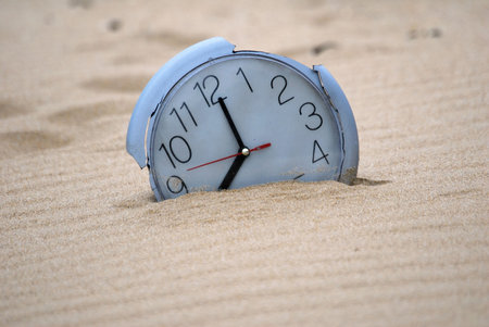 A broken clock buried in the sand.