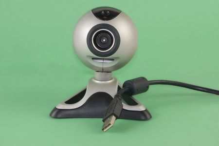 A silver webcam showing its USB connection set against a green backgroundの写真素材