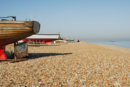 Boats that have been pulled onto the beach with a pier in the background.           の写真素材
