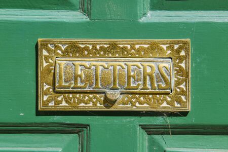 Brass letter box on a green door with the words letterd on the opening plateの写真素材