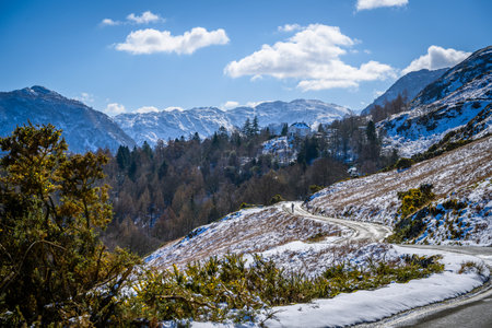 Road running down a hill in the Lake District, Cumbira, UK heading towards Borrowdale.の写真素材