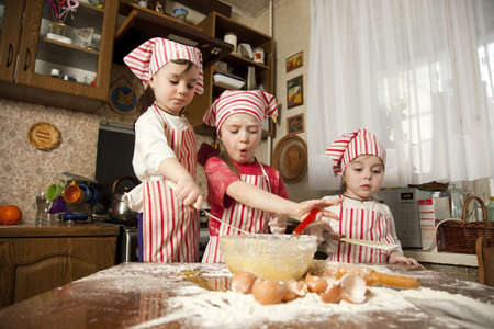 Three little chefs enjoying in the kitchen making big mess  Little girls making bread in the kitchenの写真素材