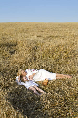 Girl with a sleeping baby in a wheat fieldの写真素材