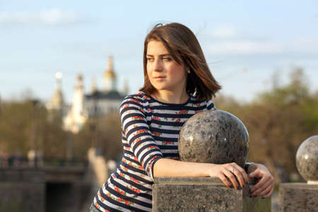 Portrait of a beautiful young girl near the ball stone in the city parkの写真素材