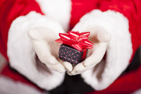 Santa Claus brings Christmas gift near the Christmas tree
