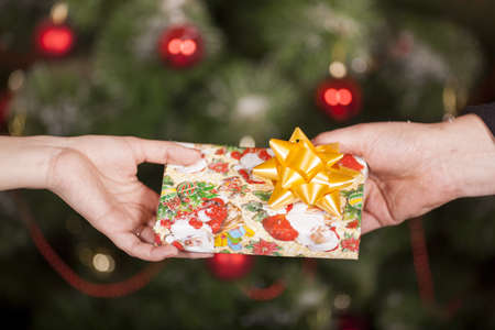 Gift delivery  between a man and a woman in front of Cristmas treeの写真素材