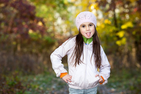 lovely girl wearing a beret showing tongue to take in the autumn forest