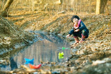 Beautiful girl on the river bank plays Paper Boatの写真素材