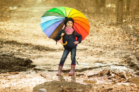 Girl with big multicolored umbrella in autumn parkの写真素材