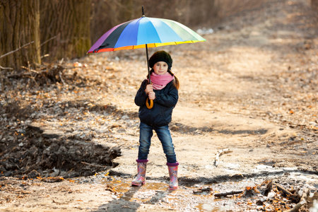 Girl with big multicolored umbrella in autumn parkの写真素材