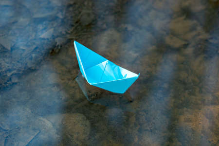 Blue paper boat in the waterの写真素材