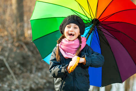 Girl with big multicolored umbrella in autumn parkの写真素材