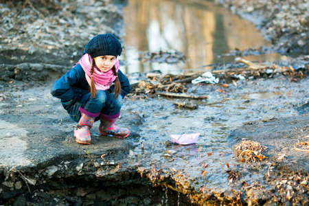 Beautiful girl on the river bank plays Paper Boatの写真素材