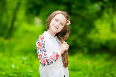 Portrait of a happy girl in the park on a background of green treesの写真素材