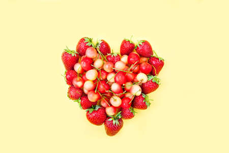 trawberries in the shape of a heart on a yellow backgroundの写真素材