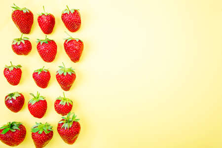 Strawberries arranged group on a yellow backgroundの写真素材